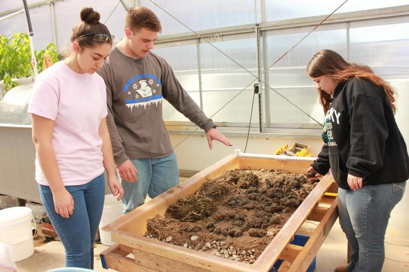 Bailey Nance (left), Jack Rogers (center), and Ann Marie Lupino (right) stand around their stream table where three different types of ecosystems are represented. The water runs down from the top of the table and the students determine which route best deterred the flowing water. BY ZARRIN TASNIM AHMED