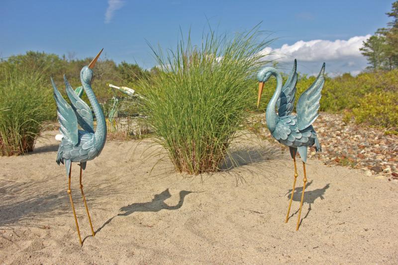 Dancing blue heron statues decorate a sandy lawn, as well as the lobster pots in the background which were used by Tracy Denton's father in Onset Bay. BY ZARRIN TASNIM AHMED