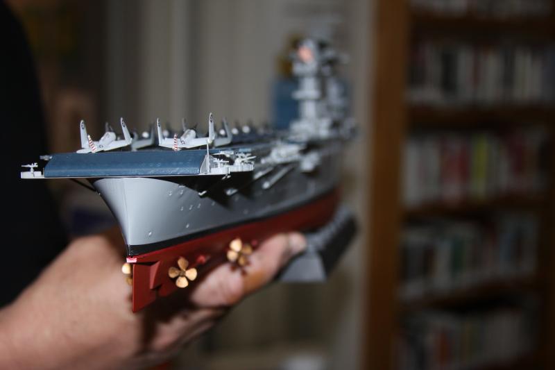 Captain John Charlebois holds up a model he built of the USS Lexington in the Wareham Free Library. That ship and others are currently on display. BY MATTHEW BERNAT