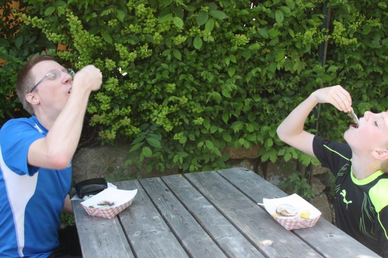 Nolen Mounier, 11, samples Big Rock Oysters with his dad Roy after finishing the Oyster Festival 5K. BY LYDIA GOERNER