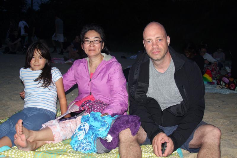 (From left) Wareham residents Dhara, Khamla and Rob Evans sit on the beach as they wait to see the fireworks. BY LYDIA GOERNER