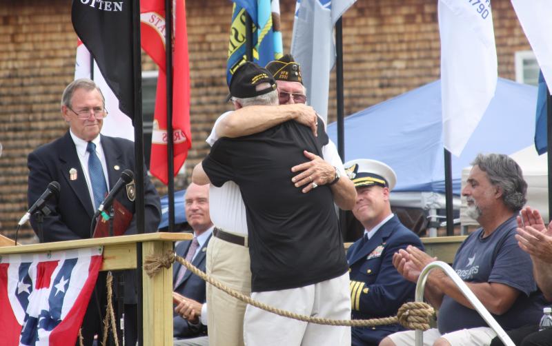 Johannes Heinrich Wagner embraces Bob White, who is wearing black, before White received an award for helping to bring The Moving Wall to Wareham. BY MATTHEW BERNAT