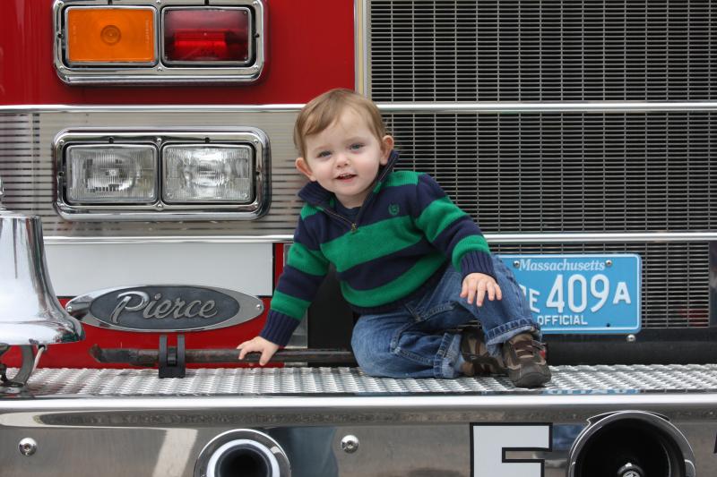Cole Hammerle, 16 months, of Wareham crawls on the front bumper of a Wareham Fire Department truck. BY MATTHEW BERNAT