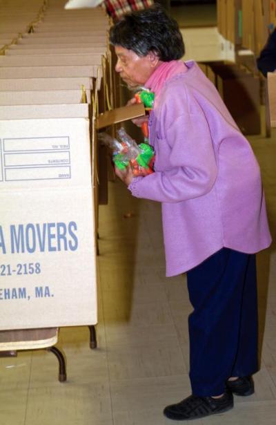 Volunteer Alice Franklin peers into a Thanksgiving meal basket to make sure that the family has enough carrots. BY ANDREW W. GRIFFITH