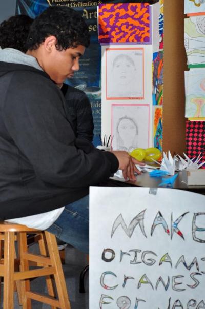Justin Suriel, a junior at Wareham High School, folds origami cranes for earthquake relief in Japan at the third annual Arts Fair. BY MATT CAMARA