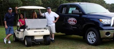 Golfer and hole sponsor Chris Fischer of G&S Marine, left, and Box 5 member Jim Franklin with Cory Ross and Rebecca Abbott, volunteers from Bailey's Surf N Turf in the golf cart. The Toyota Tundra on the right was donated by Falmouth Toyota and would have been awarded had anyone made a hole-in-one during the tournament. BY JAIME REBHAN