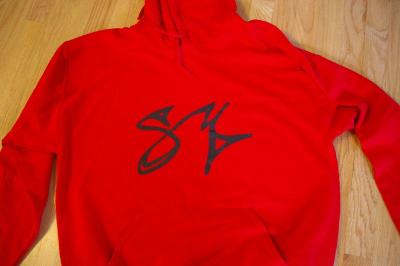 The front of a red Scotty Monteiro Jr. Foundation sweatshirt featuring his characteristic signature. BY RISHI SIDHU