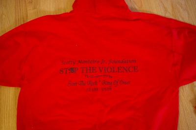 The backside of a red Scotty Monteiro Jr. Foundation sweatshirt, featuring "Scott the Rock - King of Onset" above his dates of birth and passing. BY RISHI SIDHU