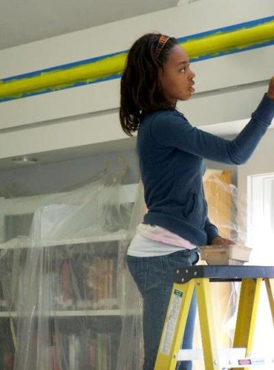 Charlemya Erasme, a member of the Teen Adviory Board from the beginning, helps paint the new teen section of the library during her Spring vacation from high school. BY LAURIE CAVANAUGH