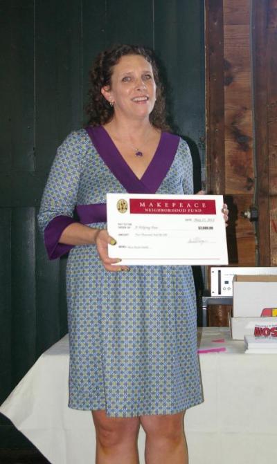 Sue Moulton, a volunteer with A Helping Paw, an animal shelter in East Wareham, accepts a $2,000 award on behalf of Helping Paw founder Chrissy Tomkiewicz to help fund its "Pat a Pet for Health" program which helps people who may be living on fixed incomes or with disabilities afford and keep their pets. BY RISHI SIDHU