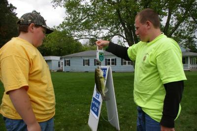Brian Holmes (right), a member of the Wankinquoah Club for 3 years, weighs a bass brought in by Brandon Lake. BY RISHI SIDHU