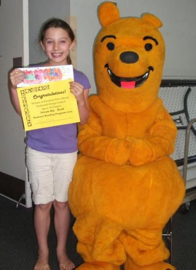 Grace Ripley, age 9, a winner of the summer reading bookmark contest, with teen volunteer Portia Lauzon in Honey Bear costume. BY WAREHAM FREE LIBRARY