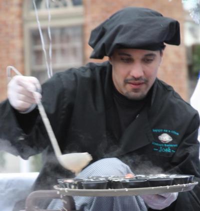 A cook from Lindsey's Family Restaurant serves up seafood bisque in the back of a pick-up truck during the parade. Fellow employees passed the samples out to the chilly parade-goers. BY JAIME REBHAN