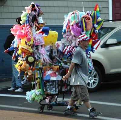 A vendor crosses Union Avenue with his wares. The fireworks show brought several vendors who sold everything from glow-in-the-dark light sticks to inflatable superhero characters. BY JAIME REBHAN