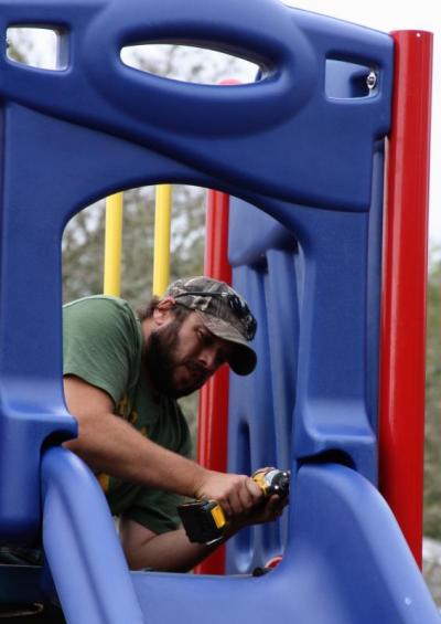Rick Mazzoli, a Decas Elementary parent, helps install a slide to the new playground. BY JAIME REBHAN
