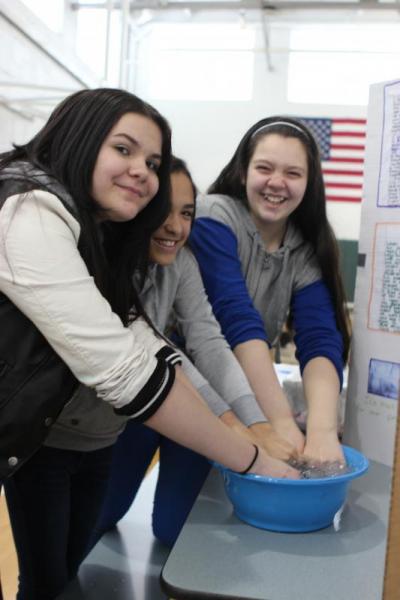 (From left) Sixth-graders Abigail Walker, Jayda Rodriguez, and Caitlin Messina dip their hands in ice cold water as part of their experiement. BY NICK WALECKA