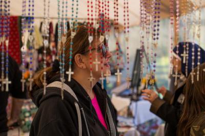 Rosaries dangle in front of Diane Ferrera's head, at a booth where nuns sold religious items. BY CAROLYN BICK