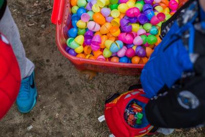 A boy with a bag full of candy stands by a bucket filled with empty shells of plastic Easter eggs. The eggs will be used again next year. BY CAROLYN BICK