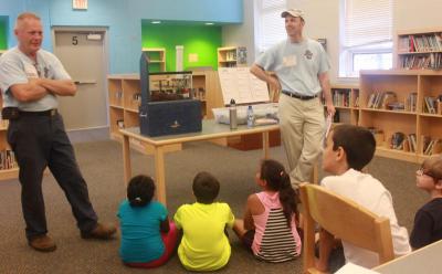 Wareham Water Department's Gregg Donahue (left) speaks to children with Andrew Reid (right) during a social outreach program. BY ZARRIN TASNIM AHMED
