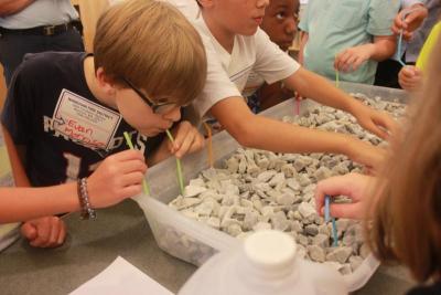 Students do their first activity for the day: sipping water that sits under rocks through straws. BY ZARRIN TASNIM AHMED