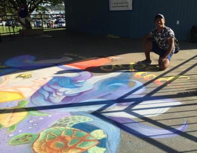 Bhen Alan of East Wareham poses next to his piece, done on the Onset Bandshell stage. Alan was the festival's featured artist this year. BY MATTHEW BERNAT