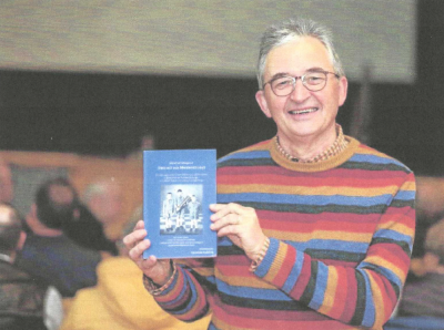 Wiegandt holds another of his published works, “Dass wir aus Meiderich sind,” a novel that details his childhood in Germany, with a particular focus on soccer. Photo by Michael Dahlke