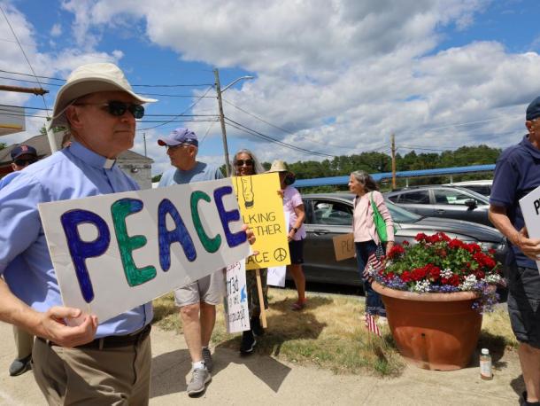 Reverend Daniel Bernier of the Church of the Good Shepherd holds up a sign for peace