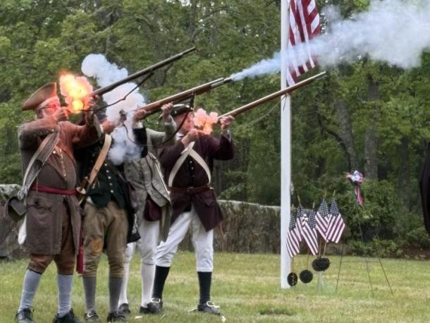 The Minutemen and Militia shoot guns dressed in period clothing.