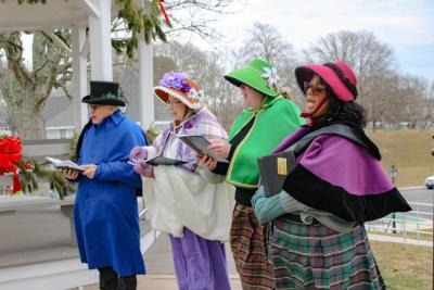 The carolers fill the street with joyful tunes.