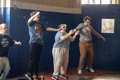 Students jump to pop music together to warm up.