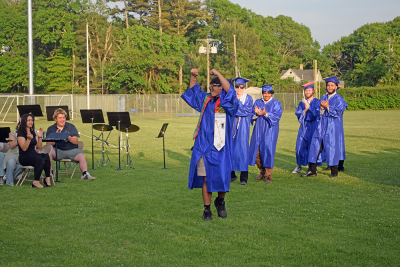 A graduate waves as he walks to get his diploma. 