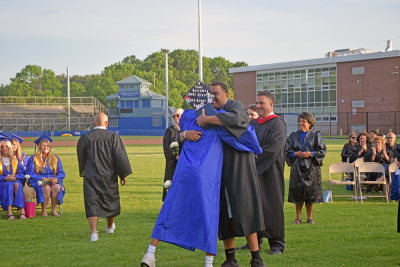 A graduate hugs the staff member that gave him his diploma. 