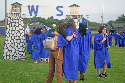 A graduate hugs their friend as they head away from the graduation. 