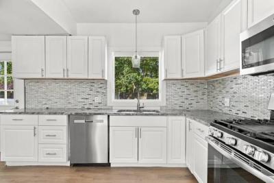 Renovated kitchen with white cabinets, granite counters, a tile backsplash and a gas range at 226 Sanford Road, Westport