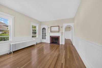 Unit 1 living room with a brick fireplace, wainscoting and an arched doorway at 370 Maple Street, New Bedford