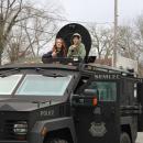 Two parade entrants on top of a military vehicle. 