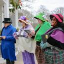 The carolers fill the street with joyful tunes.