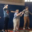 Students jump to pop music together to warm up.