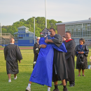 A graduate hugs the staff member that gave him his diploma. 