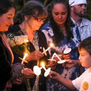 Amy Nadolny's son, Joshua Veary, 7, passes a flame between candles of family members and longtime friends during the vigil for Nadolny, Saturday, Oct. 4. Photos by Sam Tucker