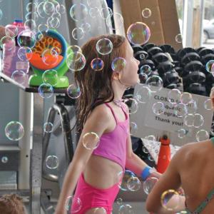 A girl dances in a cloud of bubbles.