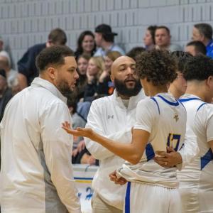 The coaching staff take a player aside during a timeout. 