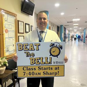 Wareham High School Principal Scott Palladino holds a sign reminding students to get to class before the morning bell. Photo by Grace Roche
