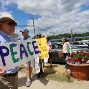 Reverend Daniel Bernier of the Church of the Good Shepherd holds up a sign for peace
