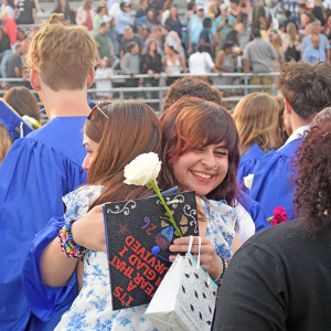 A graduate hugs their friend. 