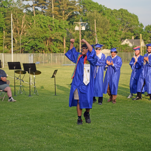 A graduate waves as he walks to get his diploma. 