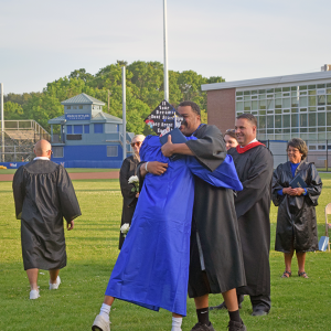 A graduate hugs the staff member that gave him his diploma. 
