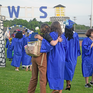 A graduate hugs their friend as they head away from the graduation. 